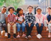 A group of young children sitting on a brick wall